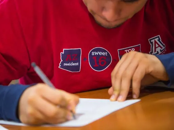 Student writing on paper